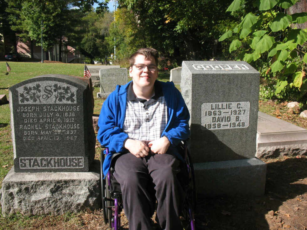 Ben in his wheelchair between two headstones at an old cemetery