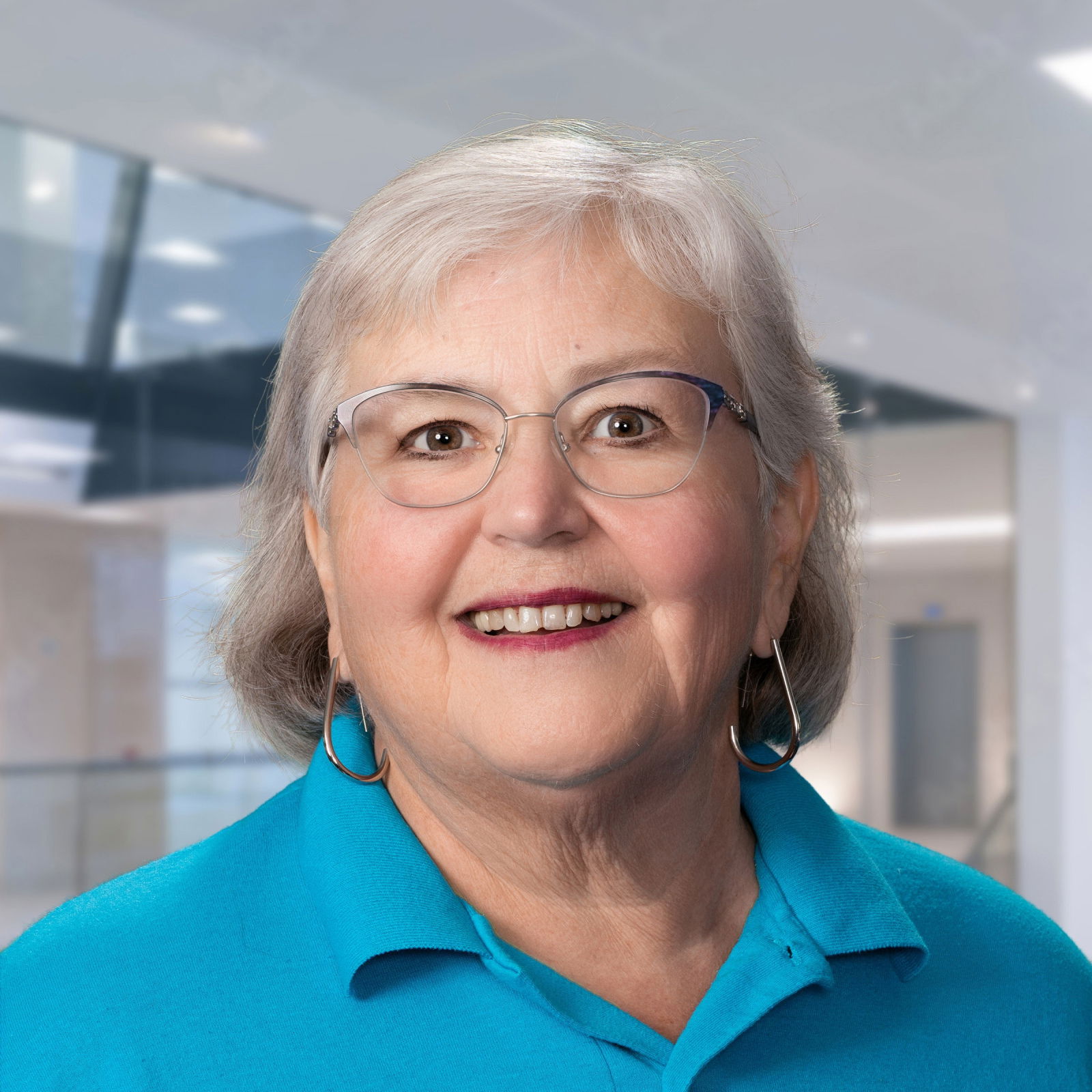 Joan Borton: woman with graying hair, a nice smile, glasses and a blue polo shirt