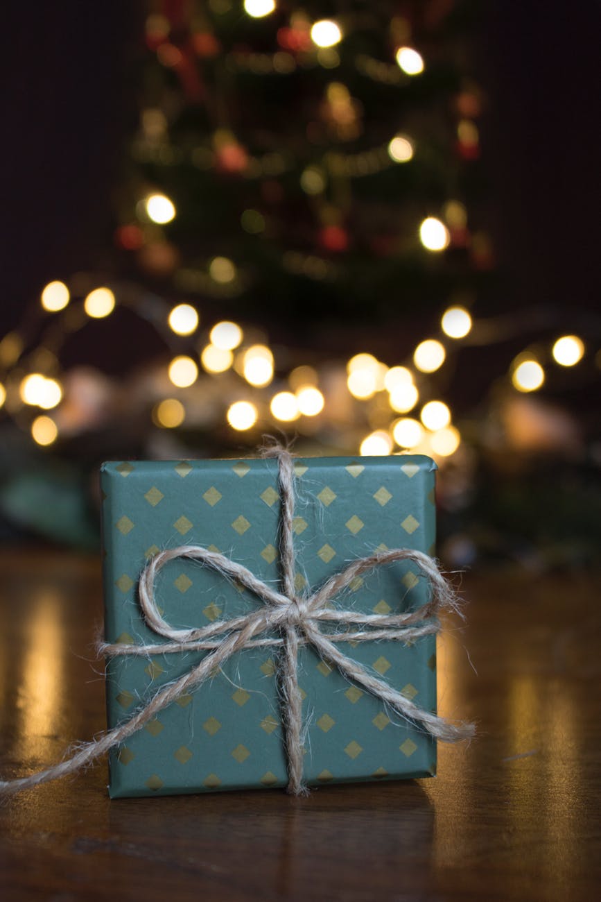 small gift in blue wrapping paper in front of a Christmas tree