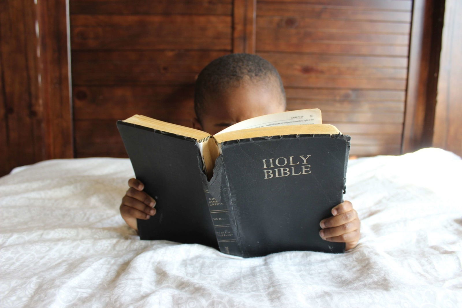 child in bed reading a well loved copy of the Bible